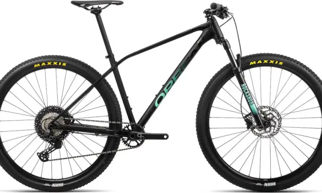 Czarny rower górski Orbea z zielonym logo. Opony Maxxis, amortyzator RockShox.