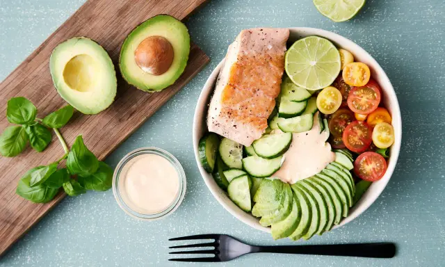 En hälsosam keto recept-bowl med lax, avokado, gurka, tomater och en krämig dressing.