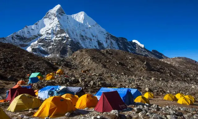 Obóz pod majestatycznym szczytem Karakorum. Kolorowe namioty rozstawione na kamienistym zboczu, gotowe na przyjęcie alpinistów.