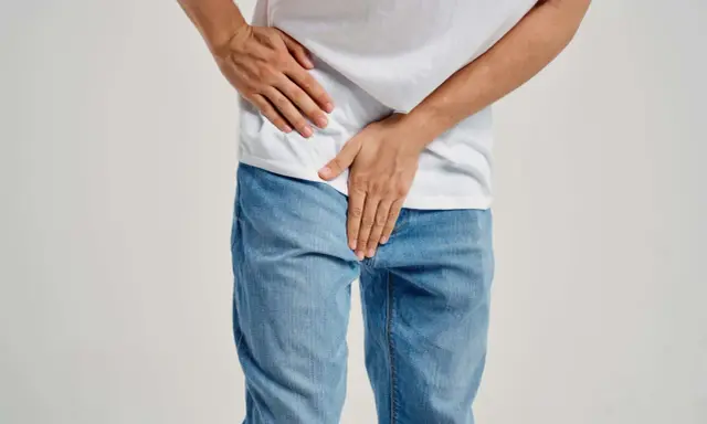 Mężczyzna trzyma się za podbrzusze, co może sugerować zapalenie prostaty objawy.