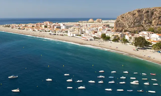 Traumhafte Küstenlandschaft an der Costa Tropical mit weißem Sandstrand, türkisfarbenem Meer und vielen kleinen Booten.