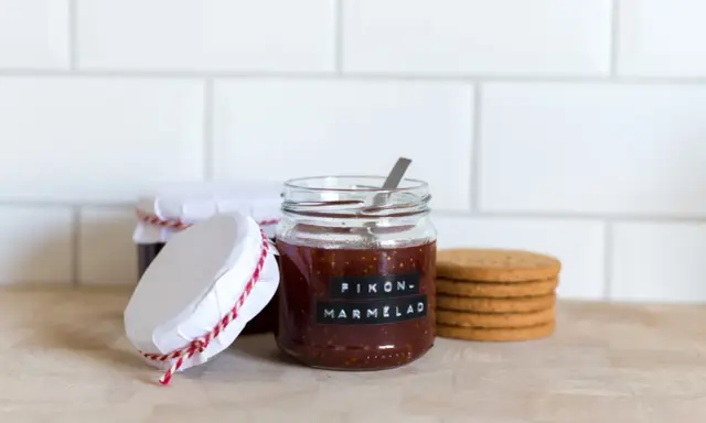 Burkar med hemlagad fikonmarmelad, perfekt för ett enkelt fikonmarmelad recept. En sked sticker upp ur den främsta burken.