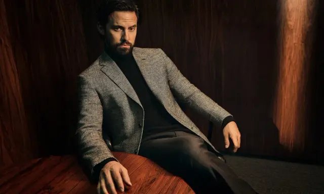 A man in a tweed blazer and dark trousers, showcasing sophisticated trouser styles.