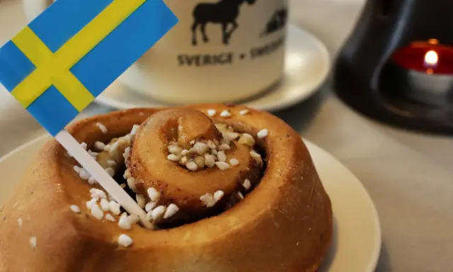 Słodka bułeczka cynamonowa z posypką i flagą Szwecji. To właśnie z takich wypieków słynie Szwecja, idealna na fika.