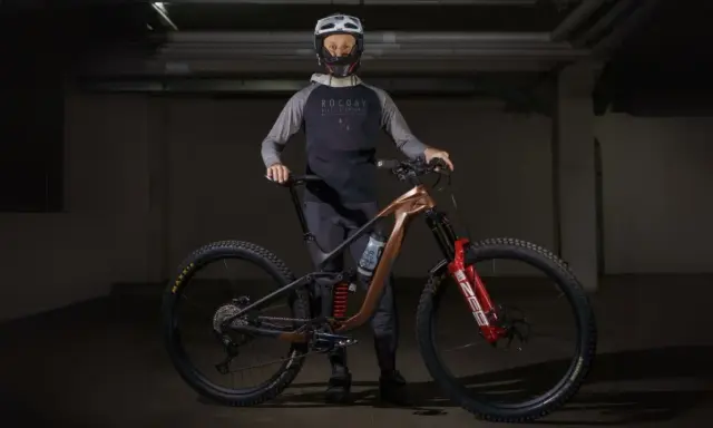 Kolarz w kasku i odzieży rowerowej prezentuje nowoczesny rower MTB. To sprzęt do ekstremalnej jazdy, a rowery mtb co to znaczy? To rowery górskie do trudnych tras.