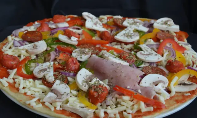 Pizza maison aux épeautre, garnie de champignons, poivrons, oignons, jambon et chorizo.