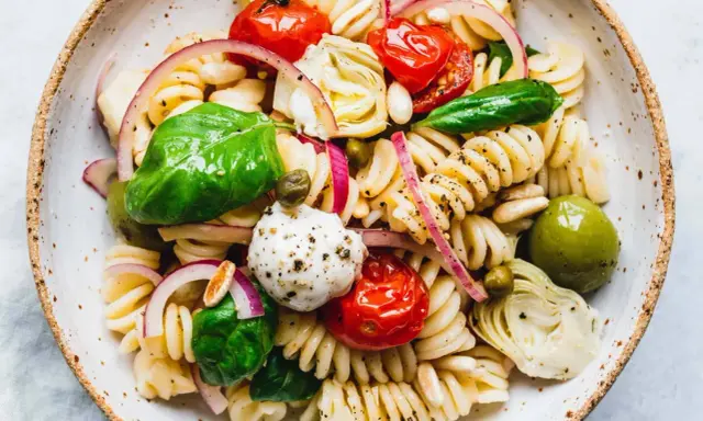 Ein bunter vegetarischer Nudelsalat mit Fusilli, Kirschtomaten, Mozzarella-Kugeln, Artischockenherzen, Oliven und frischem Basilikum.