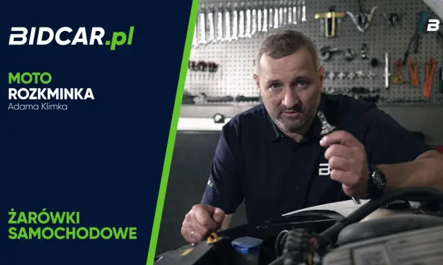 Mężczyzna trzymający żarówkę samochodową w warsztacie.