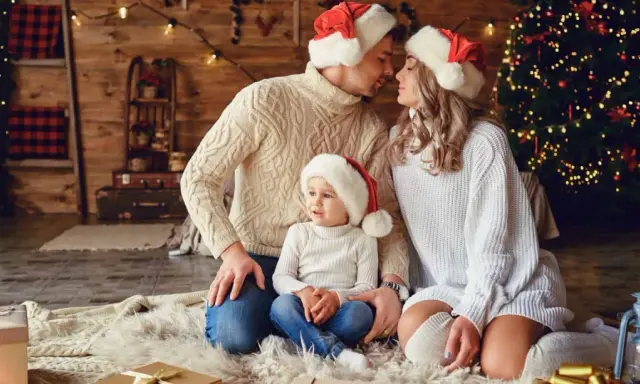 Una familia con gorros navideños, junto a un árbol de Navidad, crea una foto navidad original llena de amor y calidez.
