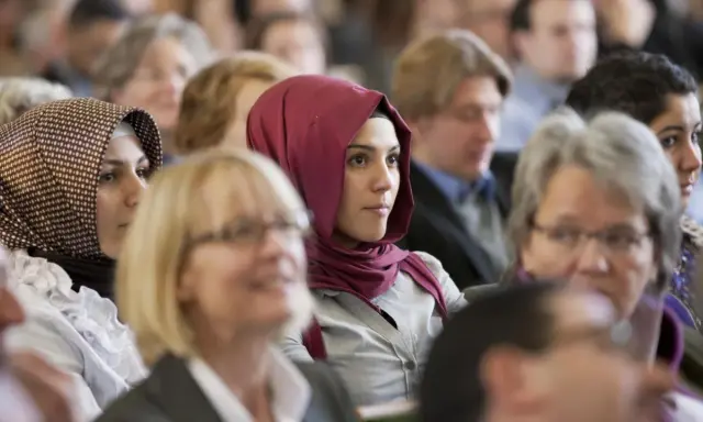 Junge Frau mit einem roten islamischen Kopftuch im Publikum.