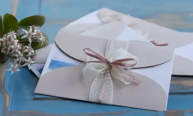 Eleganckie zaproszenia ślubne z kokardkami. Jak odmówić wesele, gdy nie możesz przybyć? Delikatne kwiaty dodają uroku.