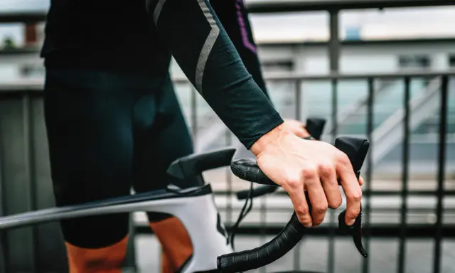 Rowerzysta z silnym bólem ud po jeździe na rowerze, trzymający kierownicę.
