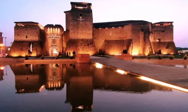 Castello Sismondo illuminato di sera, con riflessi sull'acqua. Un luogo che evoca la magia del cinema, come un museo felliniano a Rimini.