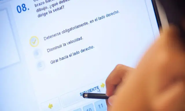 Persona haciendo un test de conducir en una tablet. La pregunta 8 es sobre una señal. ¿Cuántos test hay que hacer para aprobar el teórico?