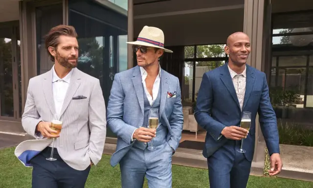 Stylish men in suits and blazers, perfect for ideas on what to wear to a wedding men. They hold champagne glasses.