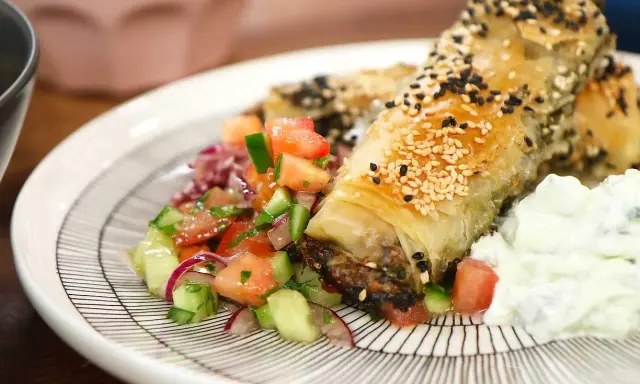 Krispiga filodegsrullar med sesamfrön, serverade med en fräsch tomatsallad och vitlökssås. Ett utsökt burek recept!