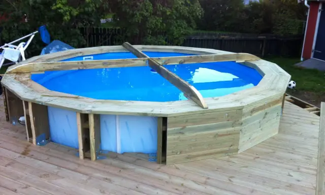 Bygga in rund pool i trädäck. En nybyggd pool med blått vatten omgiven av träpanel.