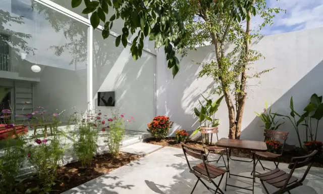 Un patio moderno con mesa y sillas de madera, flores y un árbol. ¡Excelentes ideas para porches pequeños y acogedores!