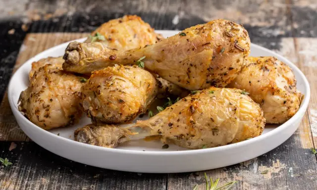 Cosce di pollo dorate e succulente, cotte alla perfezione nella friggitrice ad aria, guarnite con erbe aromatiche fresche.