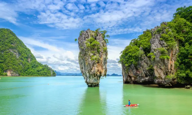 Wyspa Phuket, Tajlandia: samotna skała wyrasta z turkusowej wody, a kajakarz podziwia krajobraz.