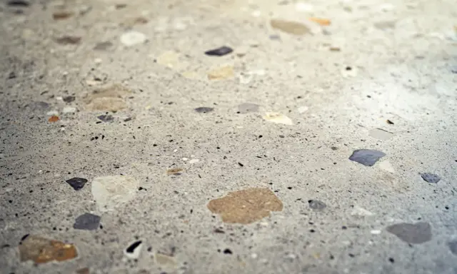 Superficie de terrazo con fragmentos de piedra de diversos colores, lista para pulir y revelar su brillo natural.