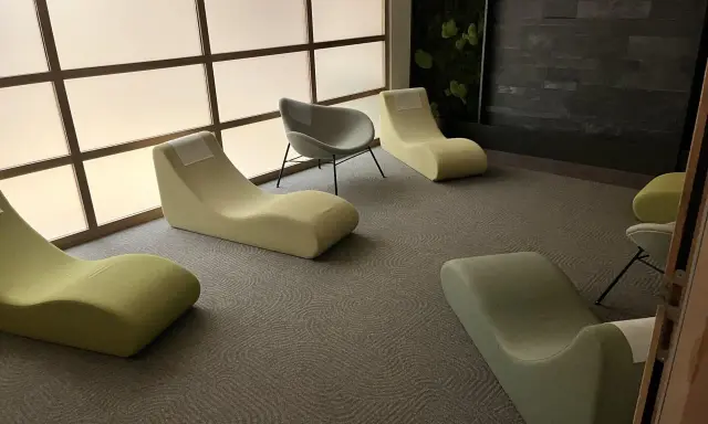 Un espace d'accueil moderne avec des chaises longues confortables et un mur végétal apaisant.