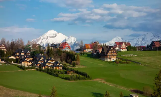 Malownicze domy w Murzasichlu z widokiem na ośnieżone Tatry. Atrakcje tego miejsca to przede wszystkim piękno przyrody i spokój.