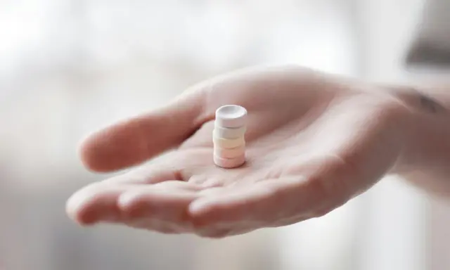 Eine Hand hält einen Stapel bunter Pillen. Vielleicht L-Arginin vor dem Schlafen für einen erholsamen Schlaf.