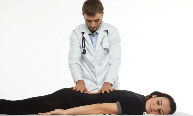 Terapeuta wykonuje delikatne ruchy na plecach pacjentki, co ilustruje, na czym polega terapia Bowen'a.