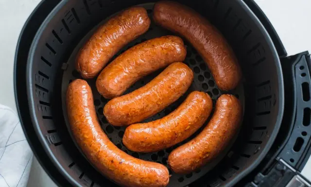 Salsiccia dorata e succulenta in friggitrice ad aria, pronta per essere gustata.