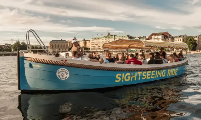 En blå båt med texten "SIGHTSEEING RIDE" tar passagerare på en tur i Stockholm.