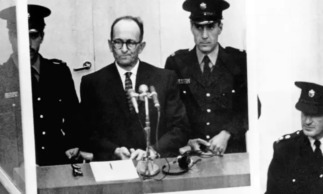 Adolf Eichmann w szklanej kabinie, otoczony strażnikami. Jego proces był transmitowany na cały świat, budząc grozę i pytania o losy dzieci.