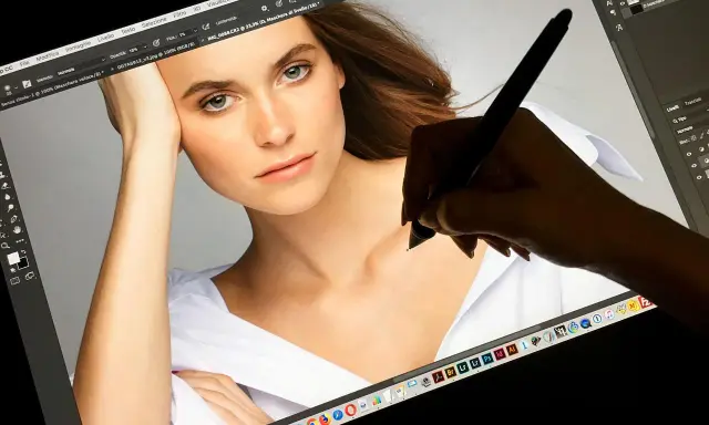 Una mano usa una tavoletta grafica per ritoccare un ritratto su Photoshop, mostrando a cosa serve questo strumento per la creatività digitale.
