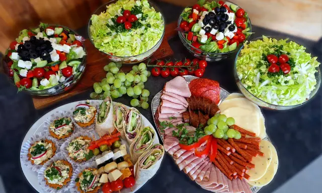 Pyszne przekąski i sałatki na talerzach. Zastanawiasz się, ile kosztuje catering do domu? To idealna opcja na imprezę!