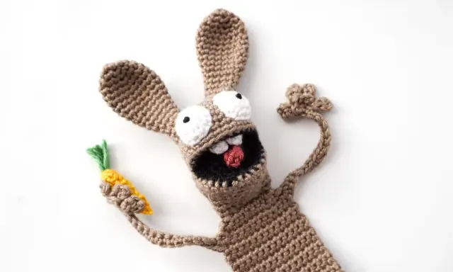 Un divertido conejo amigurumi de crochet, con ojos saltones y una zanahoria en la mano, parece listo para una aventura.