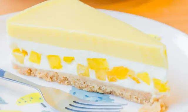 Pyszny sernik mango z kawałkami owoców i kremową warstwą na kruchym spodzie.