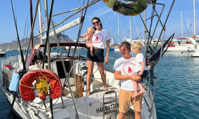 Famille souriante sur un voilier, prête pour une aventure transatlantique à voile.