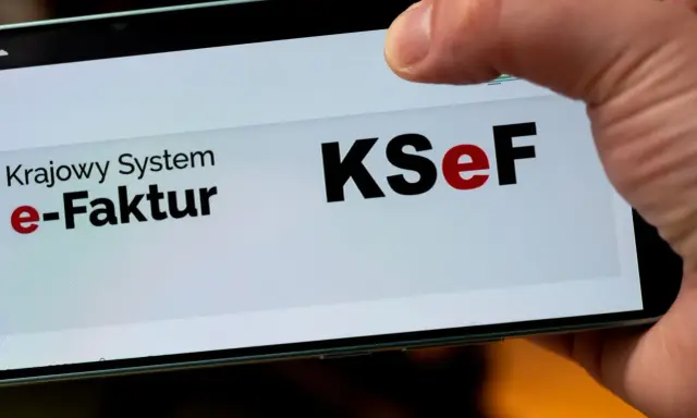 Palec dotyka ekranu telefonu z napisem "Krajowy System e-Faktur KSeF". To część polskiego ładu w finansach.