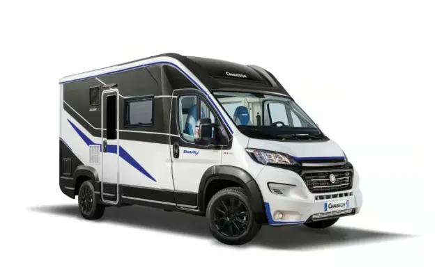 Camper elettrico bianco e nero con dettagli blu, pronto per avventure ecologiche.