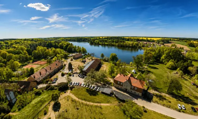 Agroturystyka nad jeziorem, gdzie można podziwiać piękne krajobrazy i odpocząć. W oddali widać pola rzepaku.