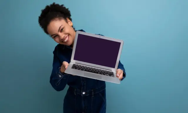 Uśmiechnięta kobieta prezentuje laptopa, gotowa do sprzedaży. Dowiedz się, jak przygotować laptop do sprzedaży, by uzyskać najlepszą cenę.