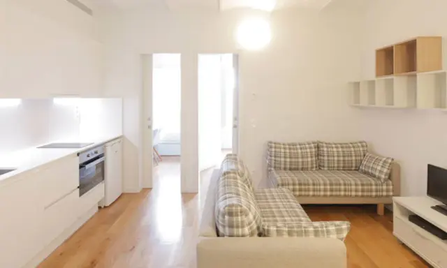 Cocina y salón modernos en la residencia Unihabit Sant Cugat. Sofás a cuadros y estanterías flotantes.