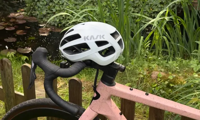 Biały kask rowerowy KASK na kierownicy różowego roweru. Przygotowany do jazdy, zgodnie z przepisami ruchu drogowego dla rowerzystów.