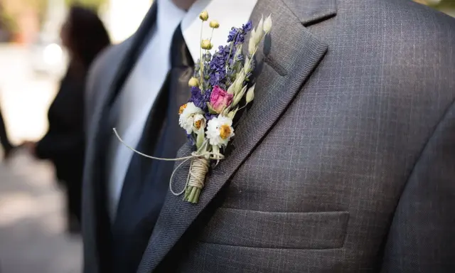 Brat weselny w garniturze, ozdobiony bukiecikiem suszonych kwiatów. Widać, kto jest kim w weselu dzięki jego eleganckiemu wyglądowi.