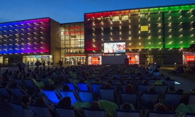 Wieczorny seans pod gołym niebem przed Galerią Krakowską. Tłum widzów w leżakach ogląda film na wielkim ekranie.