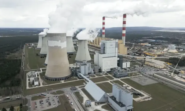 Große Kühltürme und Schornsteine einer polnischen Kraftwerksanlage, die Dampf abgeben. Der Strommix Polens wird hier sichtbar.