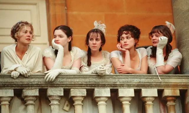 Cinque donne in abiti d'epoca, forse sorelle, riflettono su orgoglio e pregiudizio mentre guardano da un balcone.