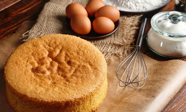 Biscuit Joconde doré, prêt pour la recette de Cyril Lignac. Œufs, farine et sucre à portée de main.