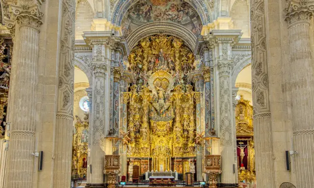 Prunkvoller Altar im Kathedrale Sevilla Innenraum, verziert mit goldenen Skulpturen und Malereien, die eine himmlische Szene darstellen.