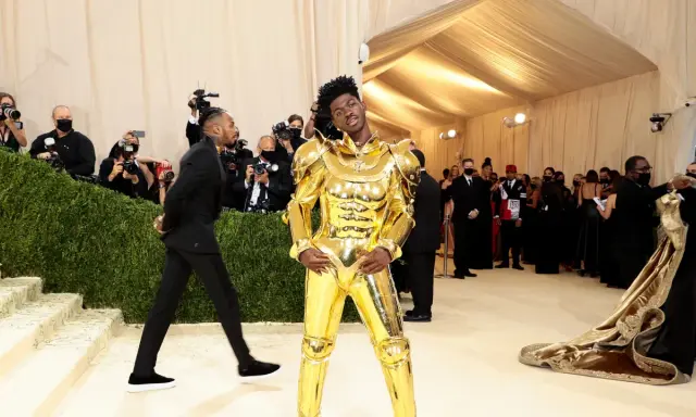 Lil Nas X, un caballero dorado, posa en la alfombra de la Met Gala, rodeado de fotógrafos y admiradores.